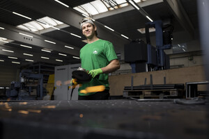 Das Foto zeigt einen Auszubildenden der MATTHÄUS SCHMID Gruppe. Er erlernt den Beruf des Metallbauers. Der Auszubildende steht an einem Schweißertisch mit einer Flex in der Hand. Die Funken sprühen. Er lacht in die Kamera.