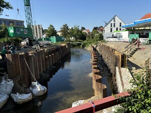 Das Bild zeigt eine Baustelle in einem Fluss. Ein Brückenbau wird vorbereitet.