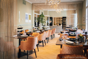 Auf dem Bild sieht man einen Gastraum eines Restaurants mit schick eingedeckten Tischen und einer außergewähnlichen Lampe