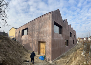 Das Bild zeigt eine Eck-Außenansicht des Neubaus der Turnhalle Weilheim in Sichtbetonwänden