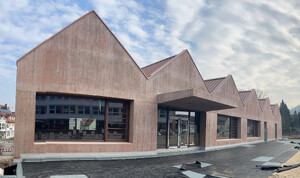 Das Bild zeigt eine frontale Außenansicht des Neubaus der Turnhalle Weilheim mit großen Fensterfronten