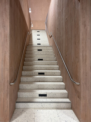 Eine Treppe in der Turnhalle, umrahmt von den roten Sichtbetonwänden