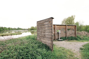 Auf dem Bild sieht man den Sichtschutz aus Holz mit einem Fernrohr zur Vogelbeobachtung