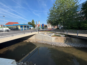 Auf dem Bild sieht man die Gründung einer Betonbrücke, neben der Straße sitzt eine Biber-Statue, im Hintergrund der Biberacher Kirchturm