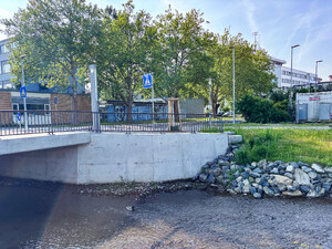 Auf dem Bild sieht man die Gründung einer neue Brücke mit Geländer, im Hintergrund ein Schulgebäude