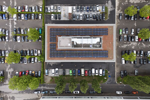 Auf dem Bild sieht man das Das Gabäude aus der Vogelperspektive, rundherum sind Parkplätze, auf dem Dach eine Solaranlage