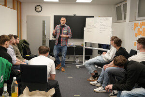 Das Bild zeigt eine Workshopsituation. Im Stuhlkreis sitzen Jugendliche, die einem Referenten zuhören.