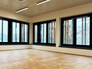 Die Abbildung zeigt eine Innenansicht des Feuerwehrhauses der Stadt Weißenhorn. Der Fotograf hat in eine Ecke gehalten. Vor den Fenstern sieht man die Fassadenteile, die über die Fenster laufen.