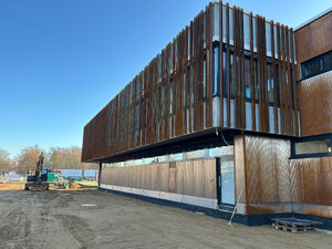 Die Abbildung zeigt eine Ansicht auf das Feuerwehrhaus der Stadt Weißenhorn. Man sieht im oberen Bereich die Fassade aus senkrechten Stahlteilen. Diese sind rostfarben. Im unteren Teil besteht die Fassade aus Holz.