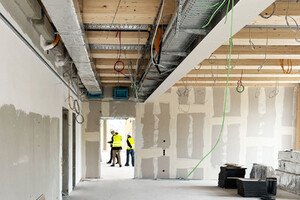 Das Foto zeigt den Innenraum eines Rohbaus. Man sieht die Holzkonstuktion des in Holz-Hybridbauweise erstellten Gebäudes.