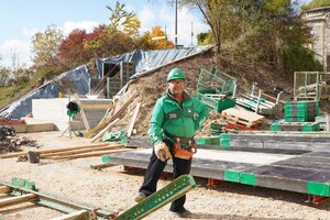 Das Foto zeigt den Kranfahrer auf der Brückenbaustelle. Hinter ihm ist das Widerlager der Brücke zu sehen.