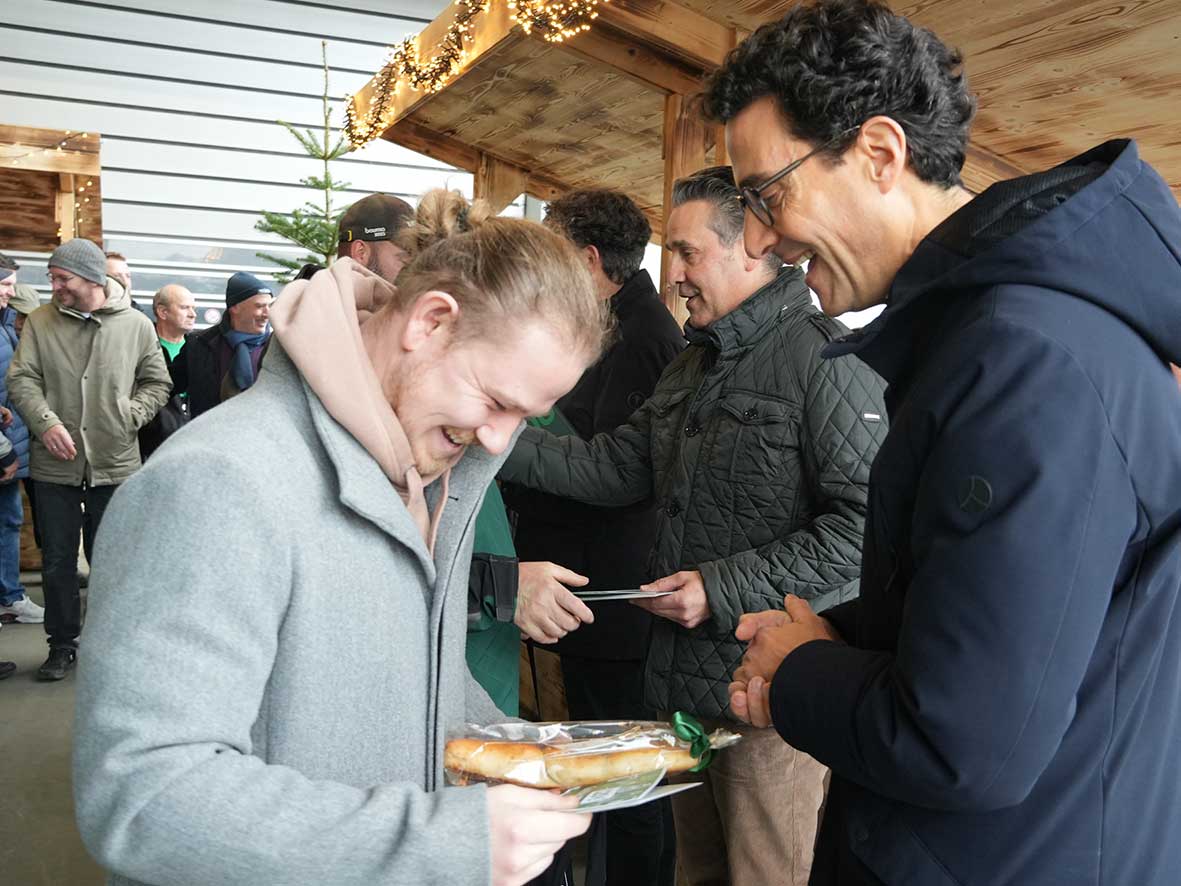 Das Foto zeigt Fridolin Schmid, wie er einem Mitarbeiter ein Geschenk &uuml;berreicht. Im Hintergrund ist Christian Schmid zu sehen, der ebenfalls ein Geschenk &uuml;berreicht
