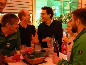 Das foto zeigt Fridolin Schmid mit Mitarbeitenden plaudernd um einen Stehtisch stehend.