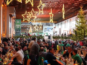 Das Foto zeigt einen Blick über die weihnachtlich geschmückte Schmid Zimmereihalle. Sie ist voller Mitarbeitender.