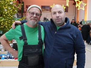 Das Foto zeigt zwei Schmid Mitarbeitende, die sich freundschaftlich umarmen. Im Hintergrund steht ein Weihnachtsbaum.