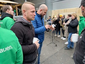 Das Foto zeigt im Vordergrund Schmid Mitarbeitende auf dem Schmid Weihnachtsmarkt auf dem Bauhof. Im Hintergrund spielt eine Besetzung des MV Baltringens