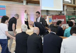 Das Bild zeigt, wie sich die Redner Platz auf ihren Sitzplätzen machen. Eine Impression vor der Bühne der Jahresbegegnung der Handwerkskammer Ulm 2026