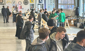 Das Foto zeigt Zuschauer, die sich in der Halle der Zimmererinnen und Zimmerer beim WettbewerbDeutsche Meisterschaft der Bauhandwerke aufhalten