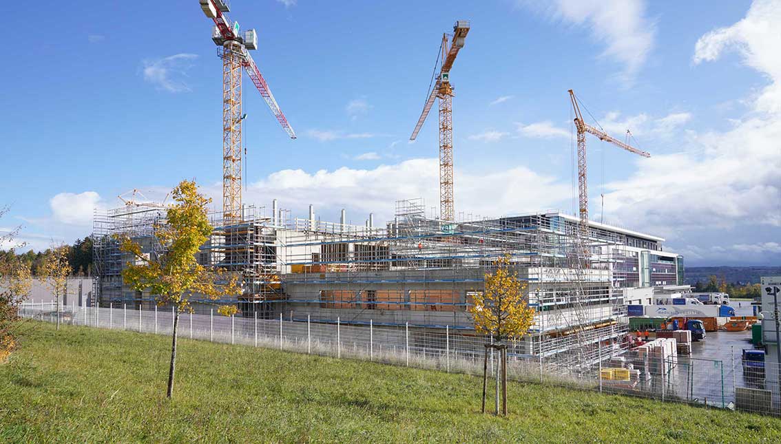 Das Foto zeigt eine Gro&szlig;baustelle mit drei Kranen.