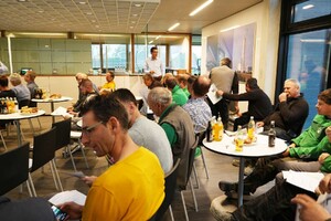 Das Foto zeigt sitzendes Publikum im Atrium des SCHMID Verwaltungsgebäudes. Das Publikum sammelt sich. Es geht gleich los.